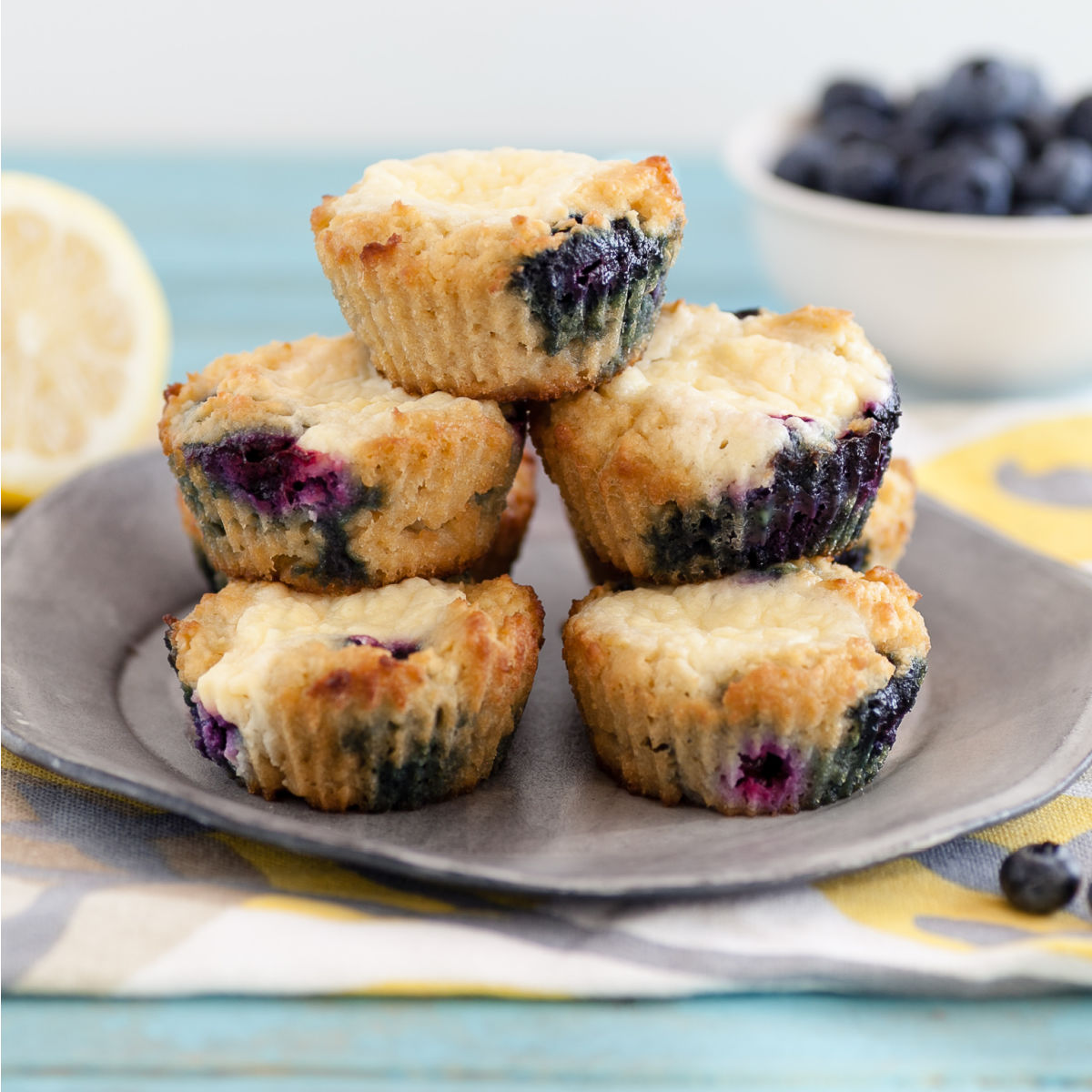A pyramid of lemon blueberry cheese danish muffins with blueberries and lemon slices in the background.