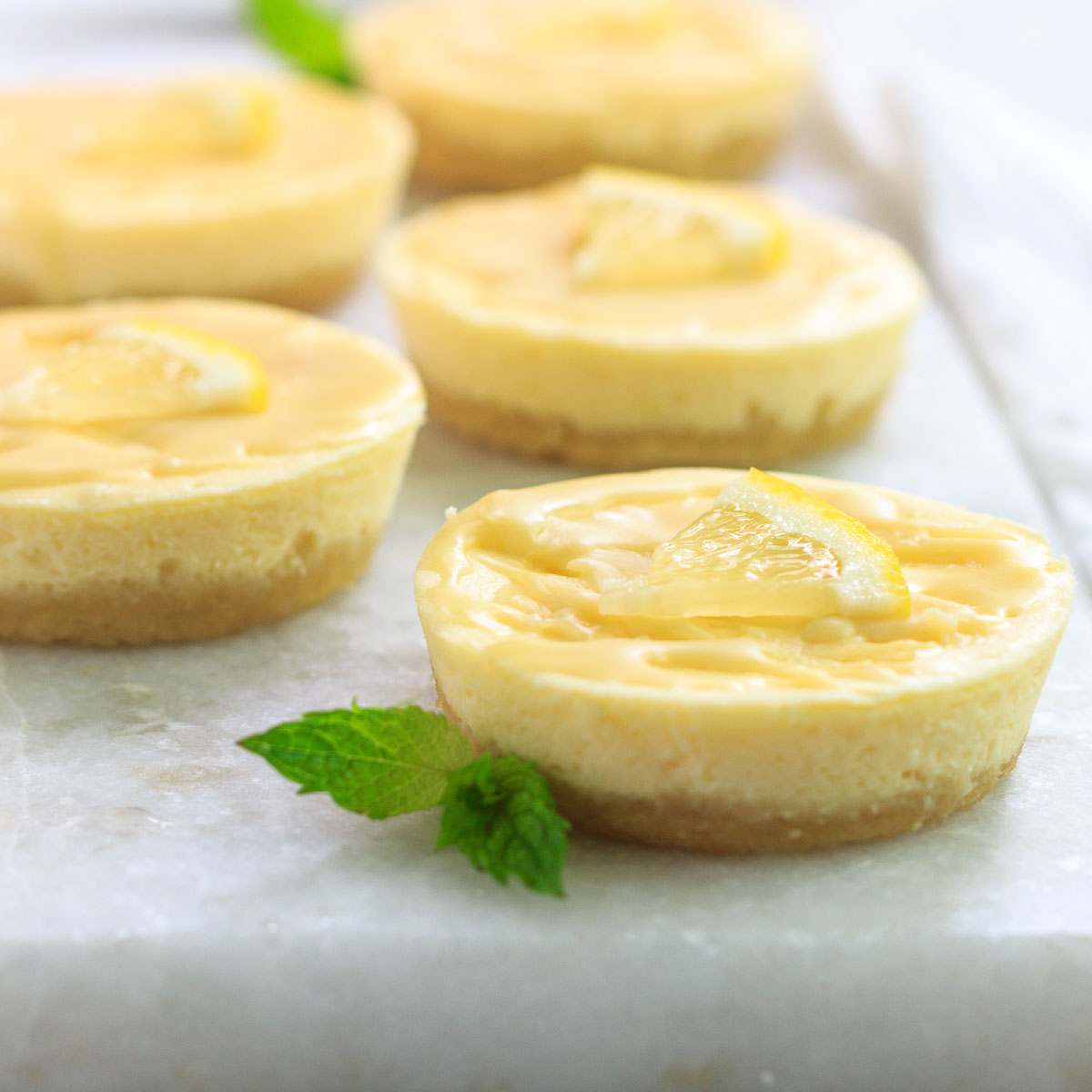 Low carb mini lemon cheesecakes with a white chocolate drizzle on top.