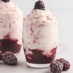Two whipped creamy blackberry desserts in shot glasses.