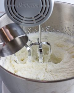 Adding sweetener and vanilla to whipping cream.