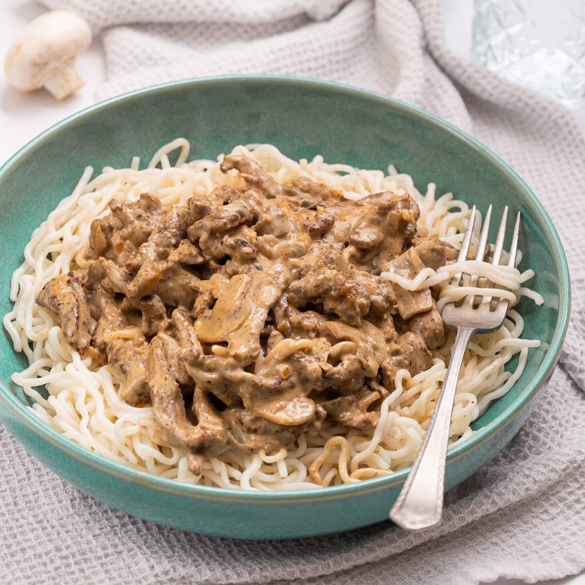 Beef stroganoff over low crab noodle in a green bowl.