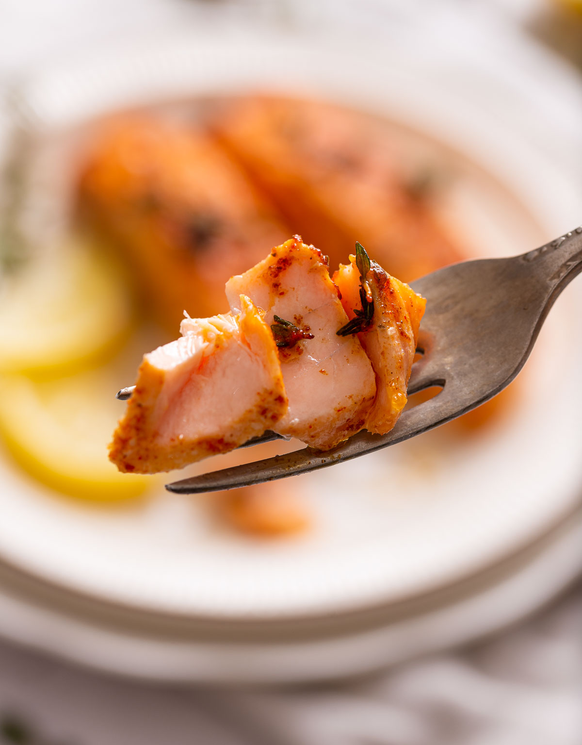 A fork with a small bite of air fryer salmon on it.