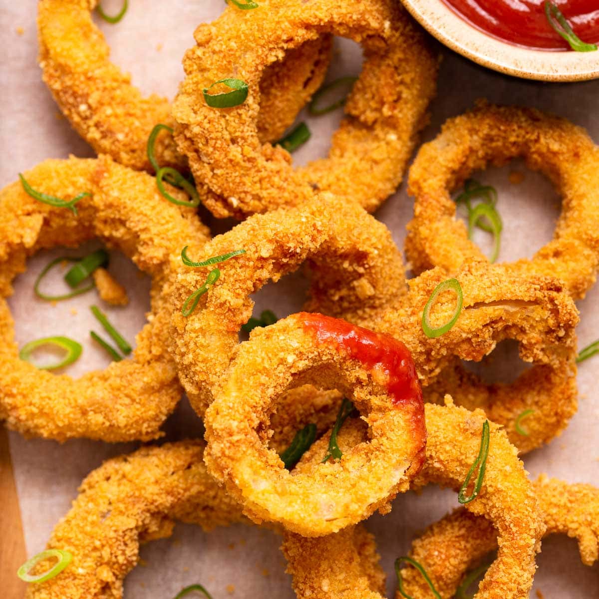 A stack of air fryer onion rings with ketchup.