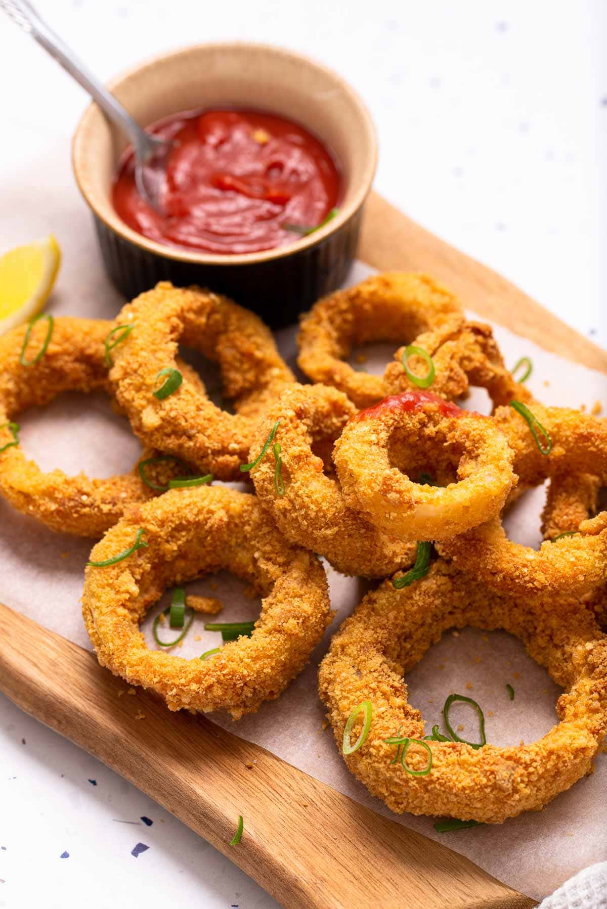 Air fried  breaded onion rings with a small bowl of ketchup.