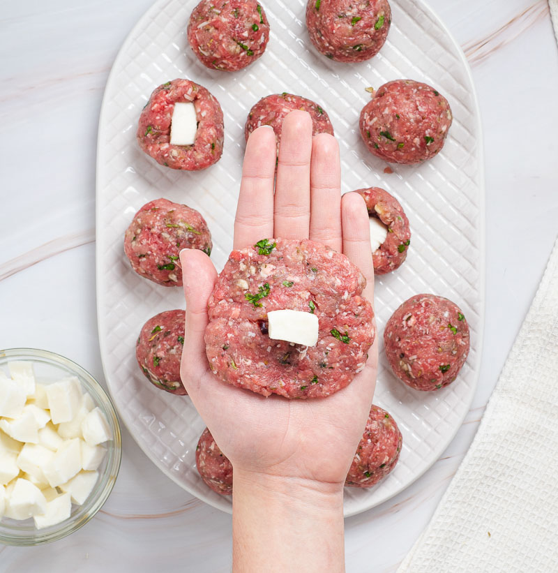 Forming the meatballs around the cheese.