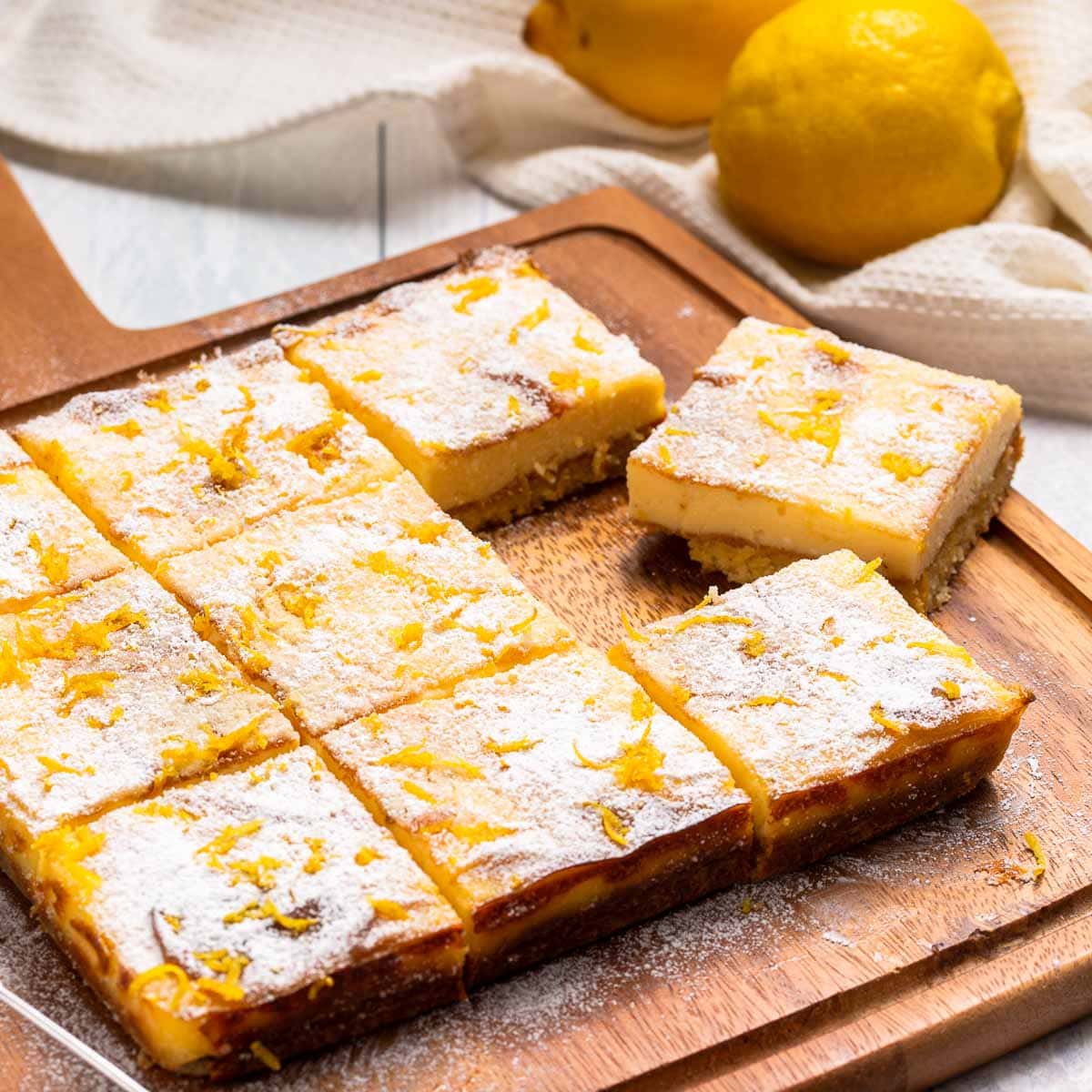 Nine keto lemon bars on a cutting board with a lemon in the background.