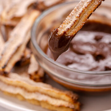 Dipping a churro into a bowl of melted chocolate.